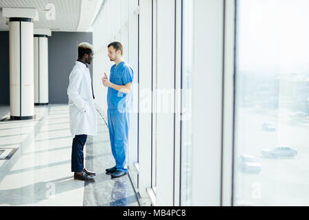 Two doctors discussing diagnosis while walking in hospital Stock Photo