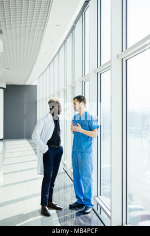 Two doctors discussing diagnosis while walking in hospital Stock Photo