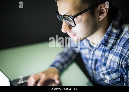 Closeup of serious focused handsome man in glasses looking at screen. Stock Photo