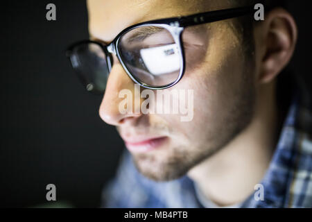 Closeup of serious focused handsome man in glasses looking at screen. Stock Photo