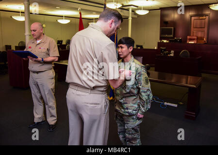 GREAT LAKES, Ill. (Feb. 14, 2018)  Naval Station Commanding Officer Capt. James Hawkins (left) awards a Navy and Marine Corps Achievement Medal to Army Staff Sgt. Jordan Siddhidhatashakti at an awards ceremony held inside Region Legal Service Office (RLSO) Midwest , Bldg. 2, Feb. 14. Early in the morning on Sept. 21, 2017, Siddhidhatashakti, along with MWR Great Lakes employee John Anderson, performed CPR on RLSO Executive Officer Cmdr. Sarah Stancanti after she saw Stancanti fall off of a treadmill inside the Bldg. 2A gym. Siddhidhatashakti and Anderson used teamwork during CPR, as Siddhidhat Stock Photo