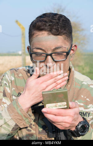 U.S. Army Spc. Jacqueline Delgado, assigned to the Chièvres Military Police at U.S. Army Garrison Benelux, applies paint on her face as she completes the situational training exercise for the garrison's Best Warrior Competition on Chièvres Air Base, Belgium, Feb. 21, 2018. Stock Photo