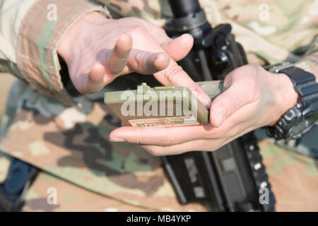 U.S. Army Spc. Jacqueline Delgado, assigned to the Chièvres Military Police at U.S. Army Garrison Benelux, applies paint on her skin as she completes the situational training exercise for the garrison's Best Warrior Competition on Chièvres Air Base, Belgium, Feb. 21, 2018. Stock Photo