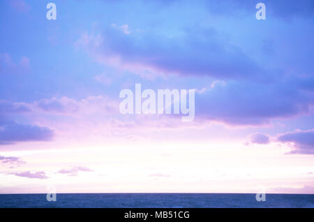 Red Sunset sky over the ocean with blue clouds Stock Photo
