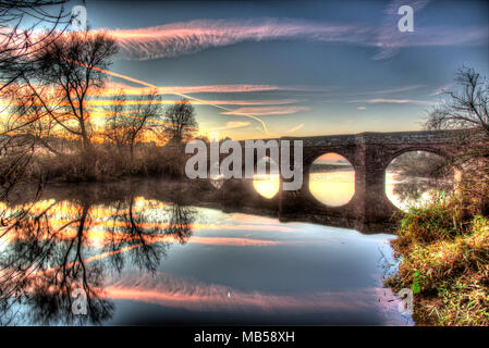 Village of Farndon, England. Artistic sunset view of the Grade 1 Listed 14th century medieval Holt Bridge over the River Dee. Stock Photo