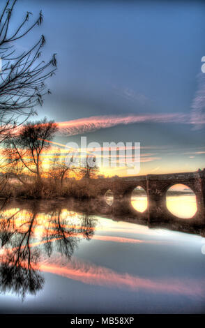 Village of Farndon, England. Artistic sunset view of the Grade 1 Listed 14th century medieval Holt Bridge over the River Dee. Stock Photo