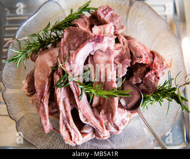 Plate with heap of lamb chops meat uncooked with rosemary herbs directly above view Stock Photo
