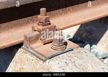 Detail of rusty screws and nut on old railroad track. Rail fastener for hold rail with concrete plinth track Stock Photo