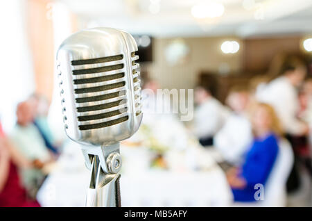 Retro microphone on light blurred background. Microphone close-up in restaurant at the banquet Stock Photo