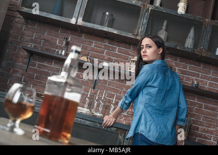 Young female alcoholic social problems standing looking back on bottle of whiskey addicted Stock Photo