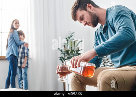 https://l450v.alamy.com/450v/mb5ak6/mother-father-and-son-social-problems-alcoholism-man-pouring-whiskey-into-glass-while-wife-with-kid-standing-near-window-scared-mb5ak6.jpg