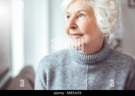 Portrait of handsome grandmother in gray sweater. Indoor, studio shoot, home interior Stock Photo