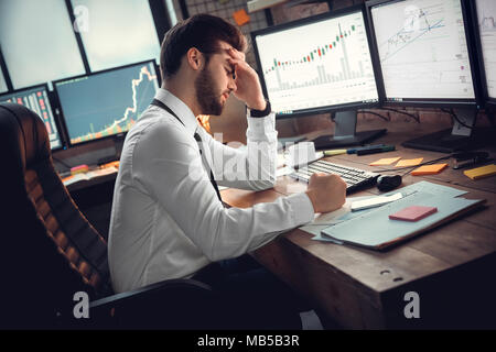 Young bearded man trader at office sitting at table touching head disappointed crisis Stock Photo