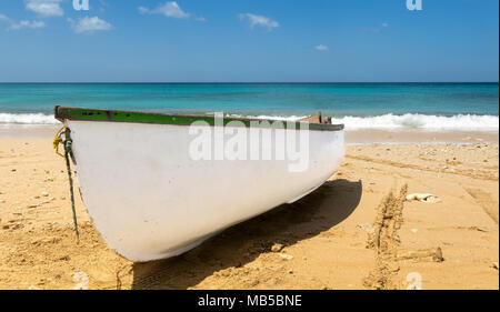 Small white row boat on a beach near the water edge. Stock Photo