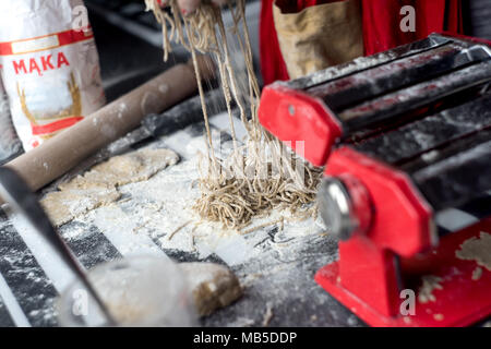 Woman preparing pasta, using red pasta grinder. Stock Photo