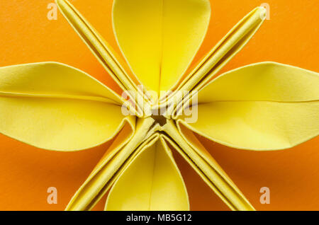 closeup of a yellow paper flower on orange background Stock Photo