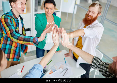 Group young business colleagues giving high five after success work Stock Photo