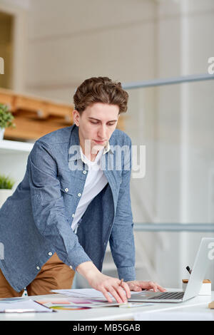 Serious designer working with patterns and using his laptop at office Stock Photo