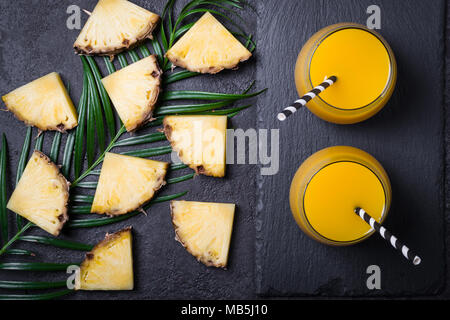 Sliced pineapple and pineapple juice or smoothies on a black background. Stock Photo