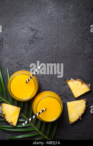Pineapple juice or smoothies and pineapple slices on a black background. Stock Photo