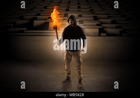 Ugly, aberrant man coming out from the labyrinth with burning flambeau on his hand  Stock Photo