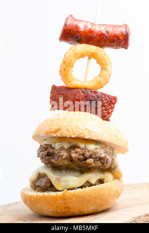 A double wild boar burger made from a boar shot in Tuscany Italy, featuring cambozola cheese and garnished with chorizo sausage and deep fried onion r Stock Photo