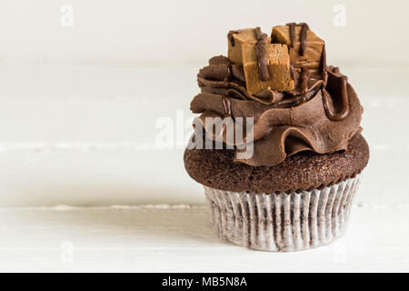Chocolate cupcake decorated with mini fudge squares on white rustic table close up Stock Photo