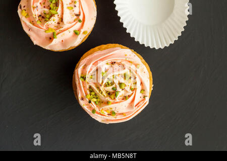 Two pink cup cakes close up on black background - Top view photo with space for text
