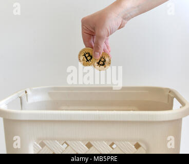 Hand throwing in a trash the coin of Bitcoin. Bitcoin concept. Stock Photo