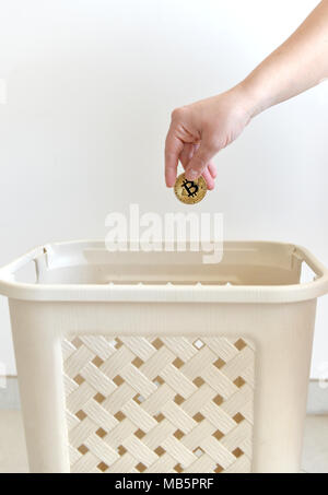 Hand throwing in a trash the coin of Bitcoin. Bitcoin concept. Stock Photo