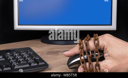 Human hand on computer mouse locked in old rusty chain. Copy space on monitor. Censorship, spy, digitization, hacking, personal data protection, GDPR. Stock Photo