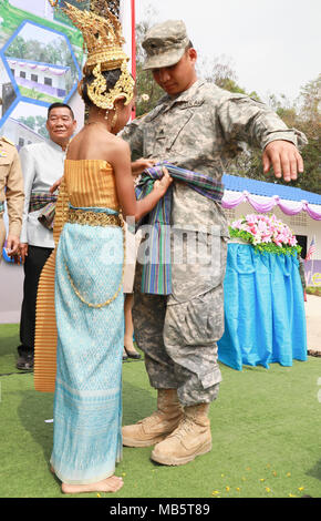 A student from Nongphipadungkitwittaya School ties a silk scarf around Sgt. Paul Anthony Atalig, a carpentry and masonry sergeant with the 797th Engineer Company, 411th Engineer Battalion, 9th Mission Support Command, during a ceremony, Feb. 22, 2018 in Korat, Kingdom of Thailand. The scarf was a gesture welcoming Atalig to the Kingdom of Thailand. During the ceremony, a newly constructed, multi-purpose building was officially opened at the school. The building was constructed by Royal Thai Army Soldiers from the 3rd Engineer Battalion, 3rd Infantry Division, U.S. Army Soldiers from the 411th  Stock Photo