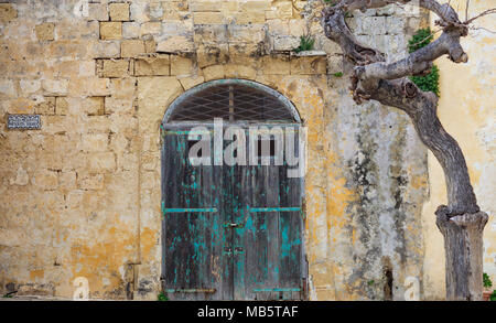 Closed old wooden door on a yellow limestone wall. Mdina, Malta, Mesquita square Stock Photo