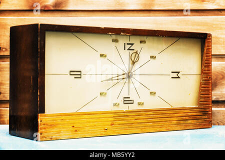 Old Rectangular clock on the background of wooden wall. The clock is decorated with wood. Stock Photo