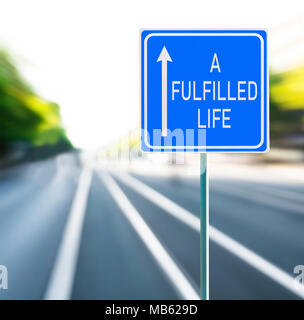 A fulfilled life motivational phrase on blue road sign with arrow and blurred speedy background. Copy space. Stock Photo