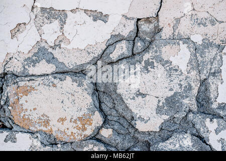 Background of natural cement plaster on the wall grey plain textured with cracks and brick in the upper right corner. The horizontal frame. Stock Photo