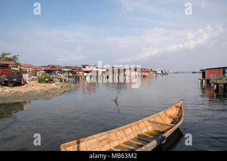 Still water by the clan jetties in George town Penang. Traditional wooden boat leading into a view of the rustic houses mounted on stilts. Stock Photo