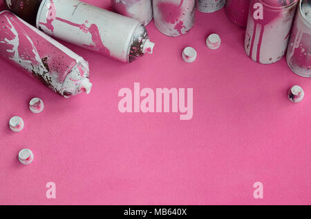 Some used pink aerosol spray cans and nozzles with paint drips lies on a blanket of soft and furry light pink fleece fabric. Classic female design col Stock Photo