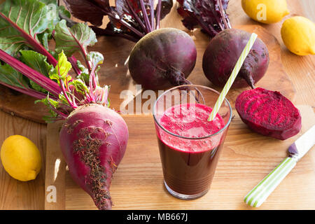 Red beet juice in a glass with whole fresh beets and lemons Stock Photo