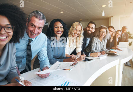 Cheerful business men and women smiling and looking at camera during coworking process in office. Stock Photo