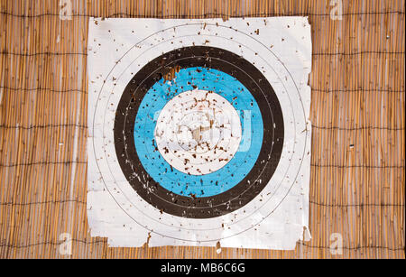 A paper archery target face with many holes torn into the target area Stock Photo