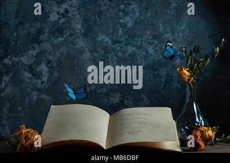 Still life an open book on the table a vase with flowers flying butterflies, a place for your text Stock Photo
