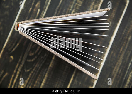 Closeup top view of side of plastic thick pages of opened family photo album isolated on brown wooden background. Horizontal flatlay photography. Stock Photo