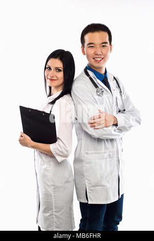Asian doctor with a smiling happy Caucasian nurse or medical colleague standing back to back with folded arms isolated on white, upper body portrait c Stock Photo