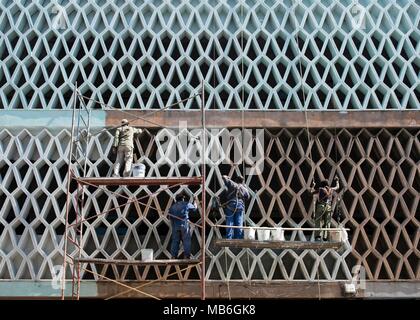 Workmen suspended on hanging platforms, paint the side of a building in  Havana, Cuba. Stock Photo