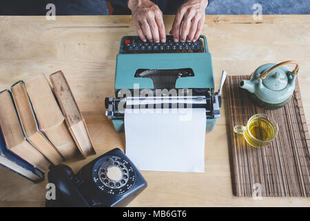 Typewriter retro with a hand of man working and accessories with tea on table Stock Photo