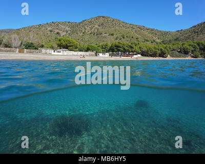 Spain coastline Cala Montjoi beach on the Costa Brava and tuft of neptune grass underwater, split view above and below surface, Mediterranean sea Stock Photo