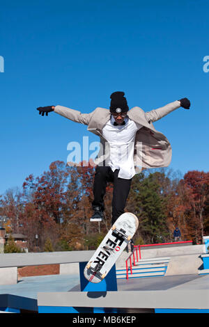A young adult skateboarder performs a jump while taking part in the grand opening weekend at the skateboard park in Kennesaw, GA on November 24, 2013. Stock Photo