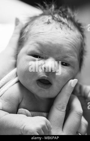 My partner gently strokes the soft cheeks of our new born baby a few hours after she is born in hospital. Stock Photo
