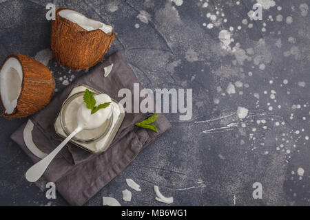 Coconut yogurt in a glass jar on dark background, copy space. Healthy vegan food concept. Stock Photo